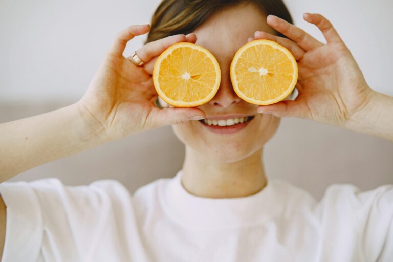 A person holds two oranges up to their eyes.