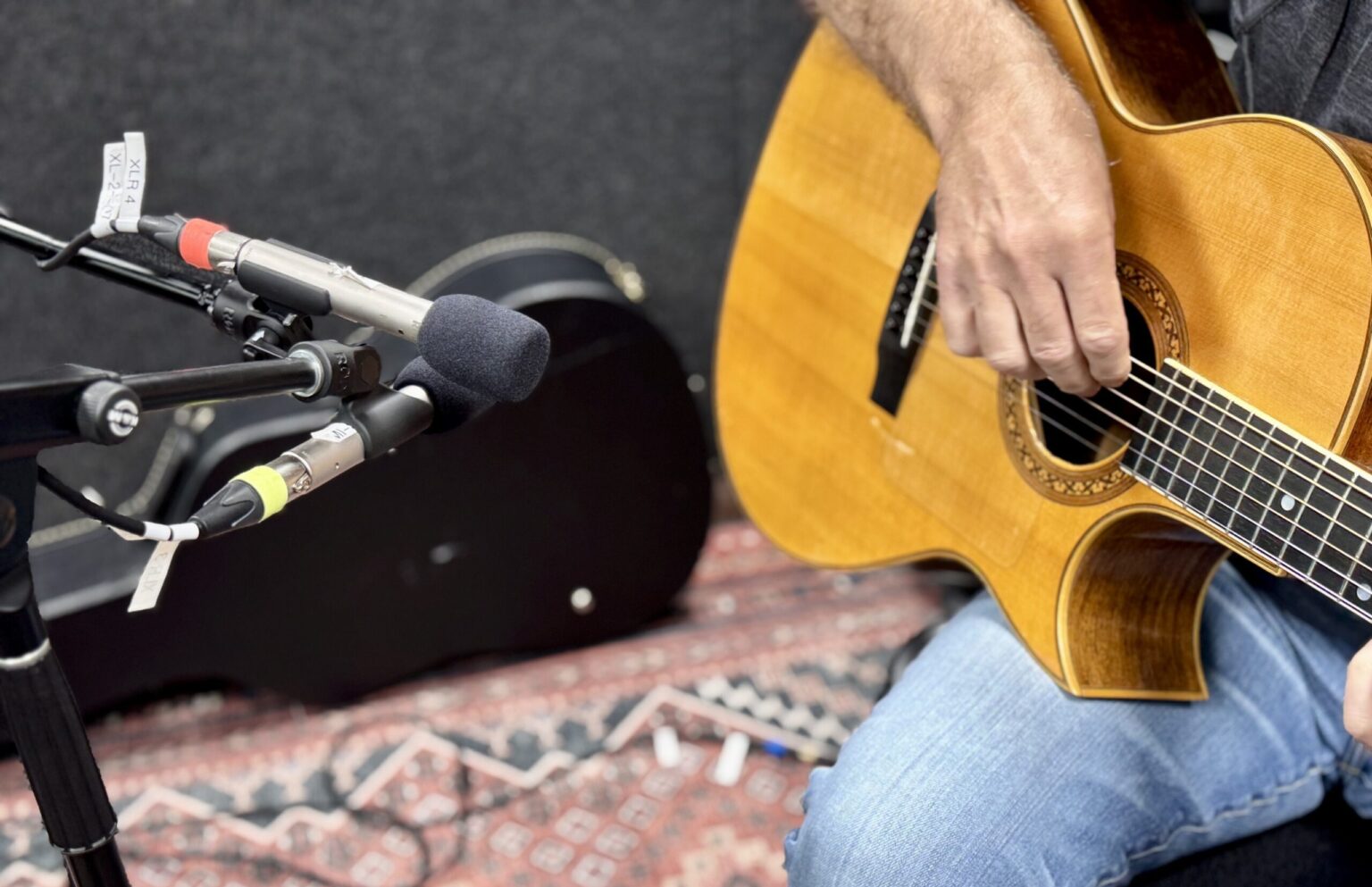 A guitar is played next to a microphone recording sound.