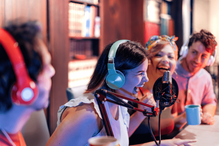 Four adults wearing headphones laugh.