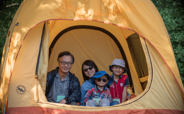A famiy smiling inside of a tent. 