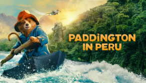 Movie poster for Paddington in Peru showing Paddington the bear wearing a red rain hat and blue rain jacket paddling down a river in an upsidedown umbrella. 